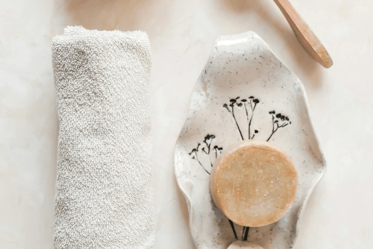日初而皂手工圓形肥皂放置於手繪花卉陶瓷皂盤上，旁有白色質感毛巾