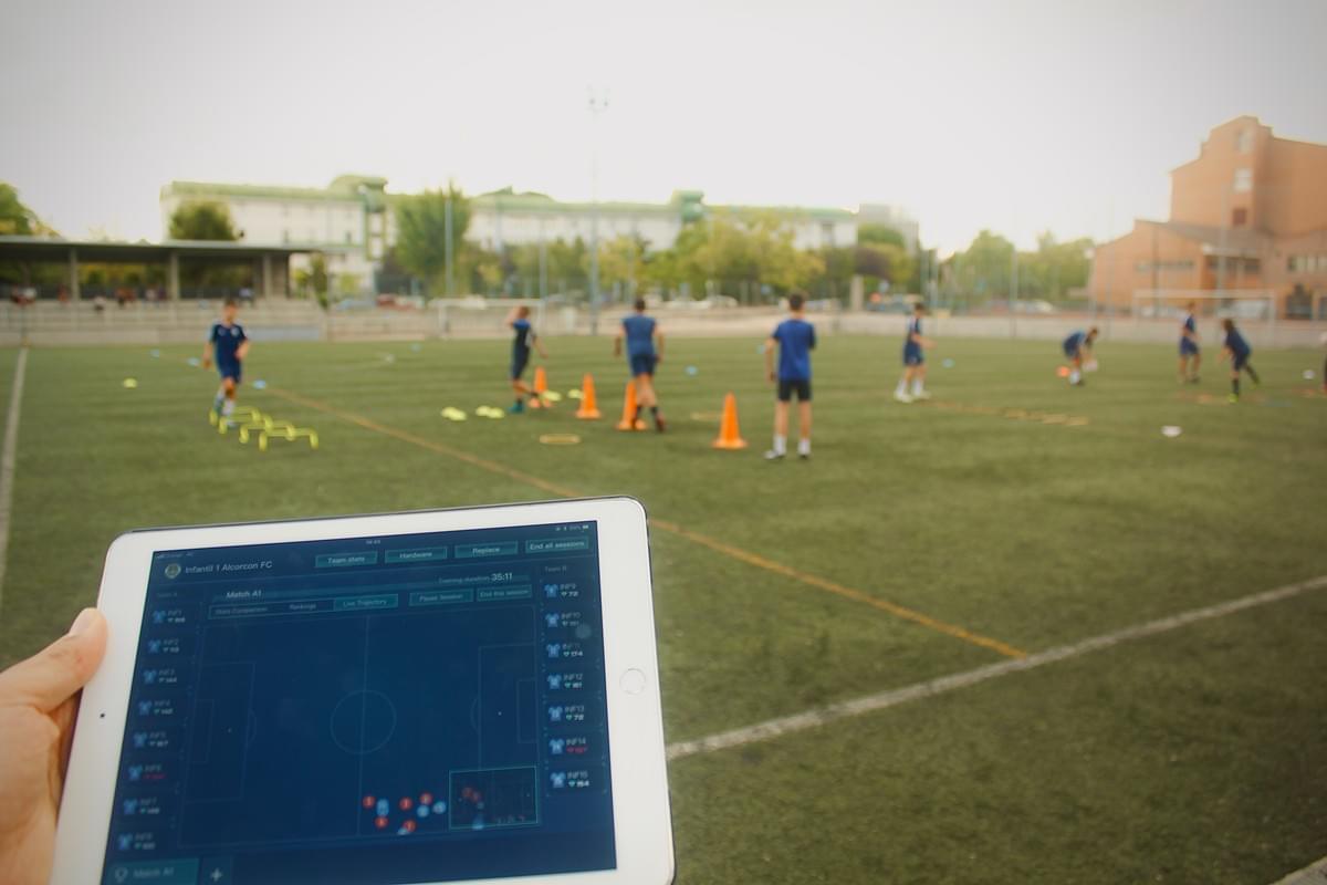 A coach at AD Alcorcón in Spain reviewing real-time player training load data on an iPad, powered by the INSAIT KS UWB tracking system.