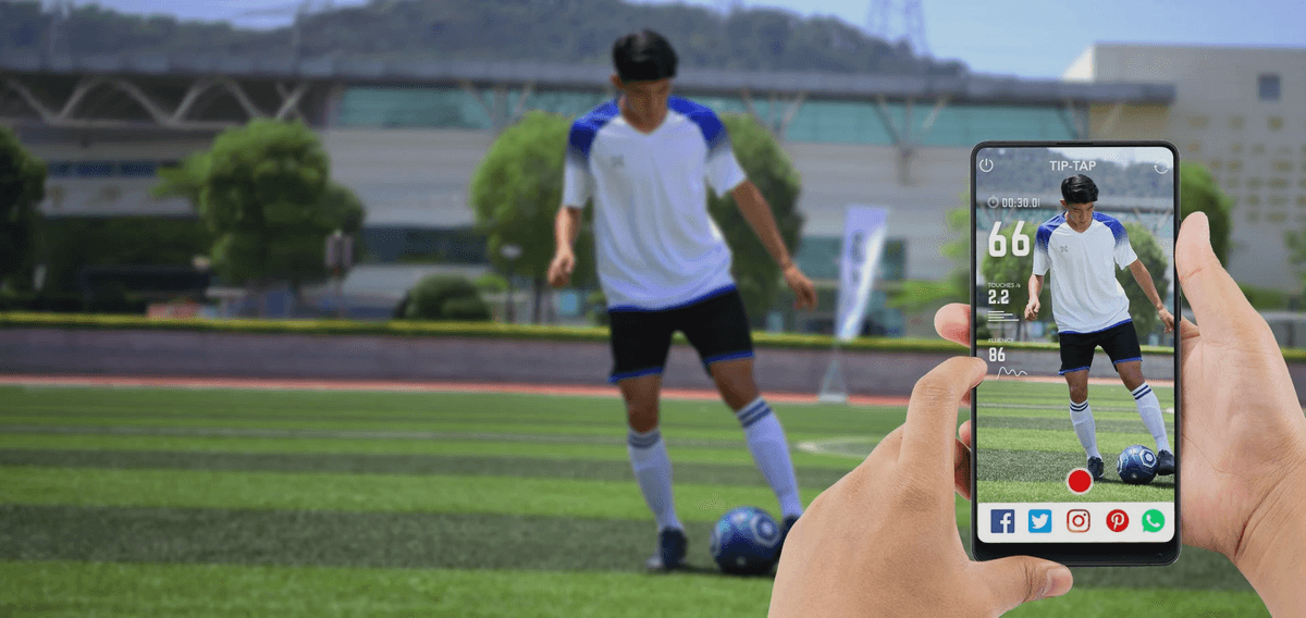 A parent using the INSAIT JOY App to record a youth football training video with real-time data overlays from the smart football, capturing their child's progress and achievements.