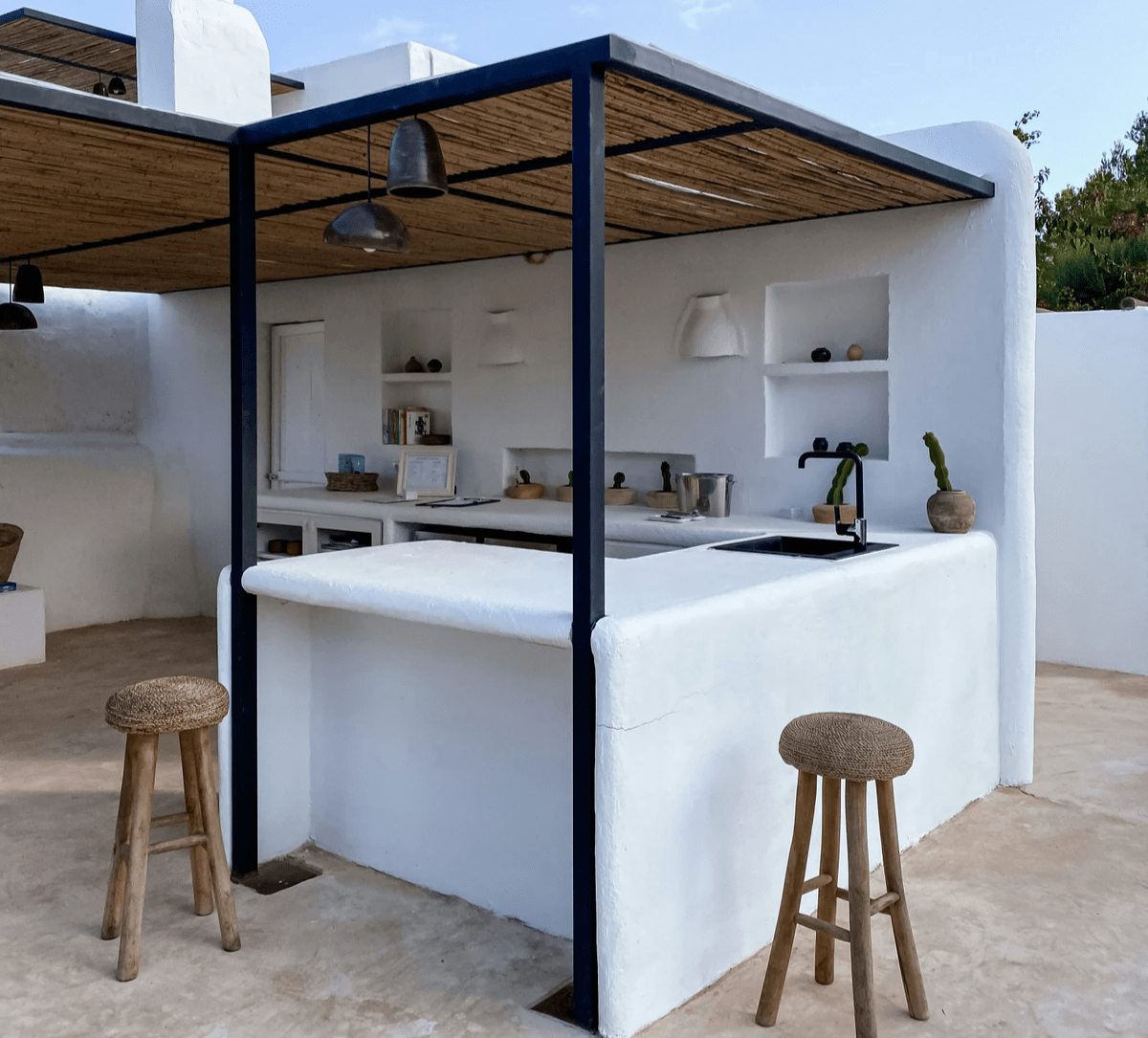 Adobe style outdoor kitchen with metal pergola and wood covering. Custom outdoor kitchen and patio builder Midland