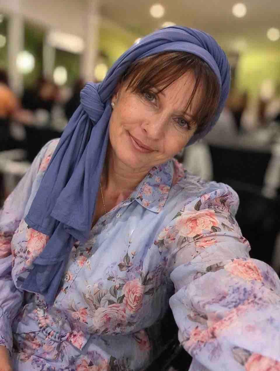 Photo of Shazzy a pale female presenting person in a blue dress and scarf in her wheelchair at a wedding 