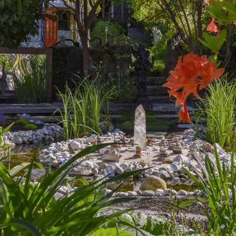 Jardin paisible qui invite à se ressourcer, avec de la végétation, un cristal et un cour d'eau