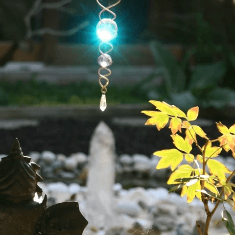 Dans un jardin, une statue de dos d'un bouddha observe un cristal et une décoration en spirale