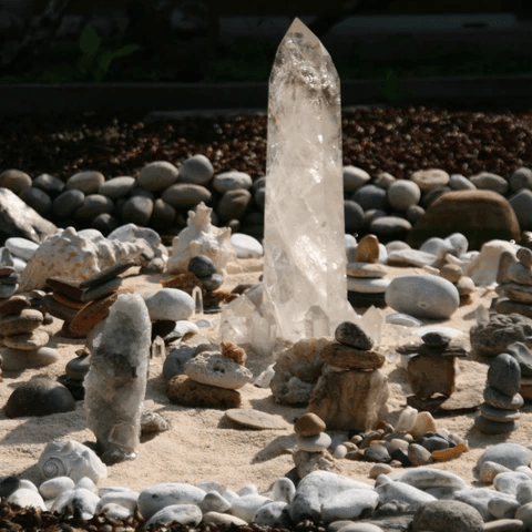 Cristal posé sur du sable et entouré de cailloux et coquillages