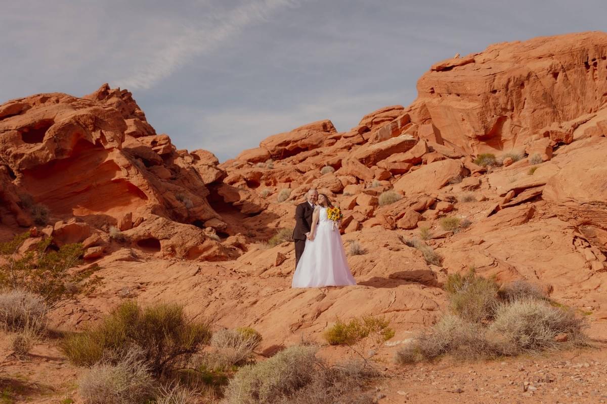Couple in elegant wedding attire posing against the dramatic red sandstone formations of Valley of Fire State Park, captured by Falling Rocks Photography.