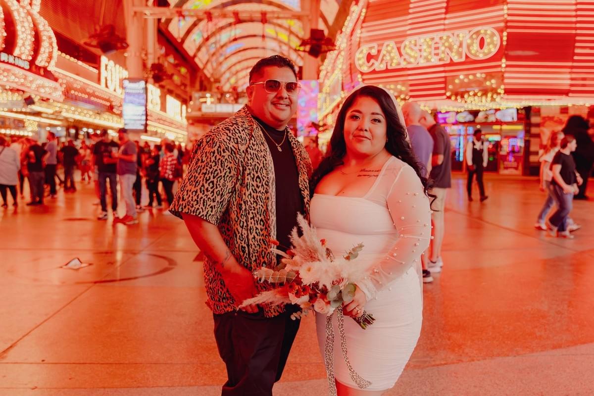 Urban elopement photography on Fremont Street featuring a couple in wedding attire under the vibrant neon lights of downtown Las Vegas.