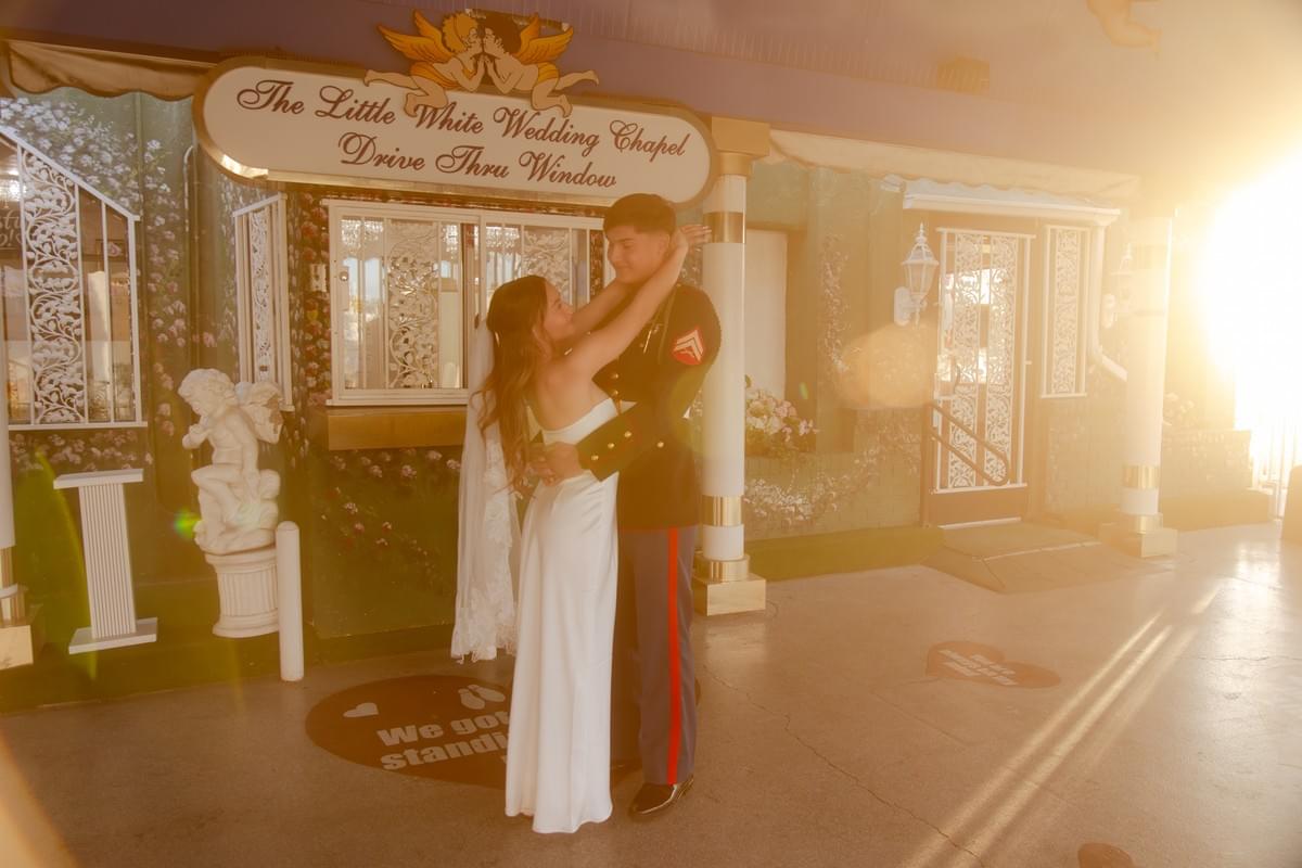 Couple in wedding suit and dress celebrating at the Little White Chapel drive-thru window during golden hour in Las Vegas, by Falling Rocks Photography.