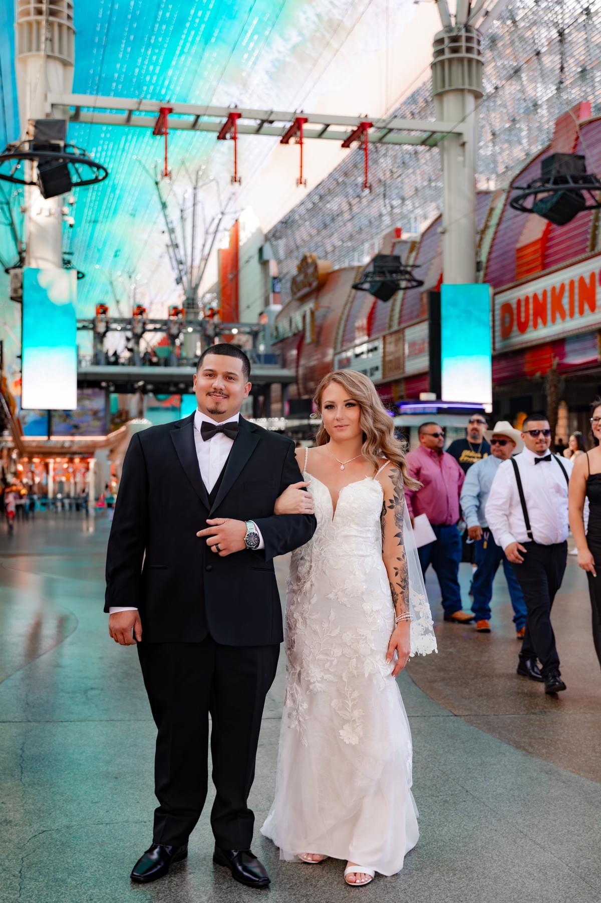 Couple walking hand-in-hand along Fremont Street in Las Vegas after their elopement, smiling and enjoying the neon lights.