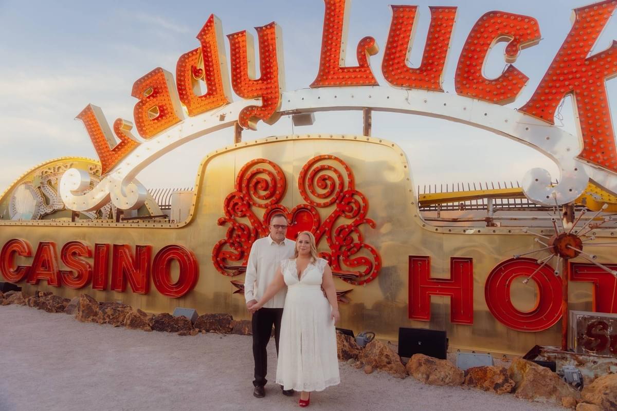 A couple in stylish elopement attire surrounded by iconic vintage signs at the Neon Museum "Boneyard" in Las Vegas, by Falling Rocks Photography.