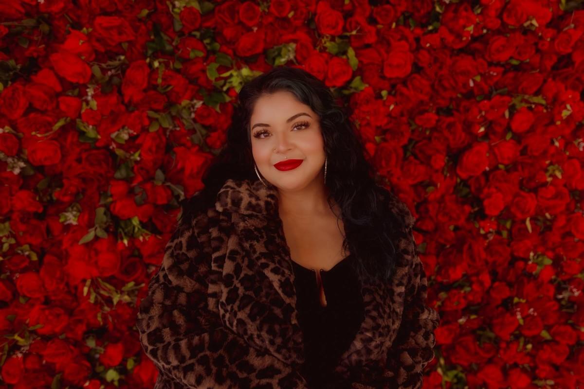 Professional female portrait with a custom set design featuring a lush rose background at The Gathering Place studio, styled by Falling Rocks Photography.