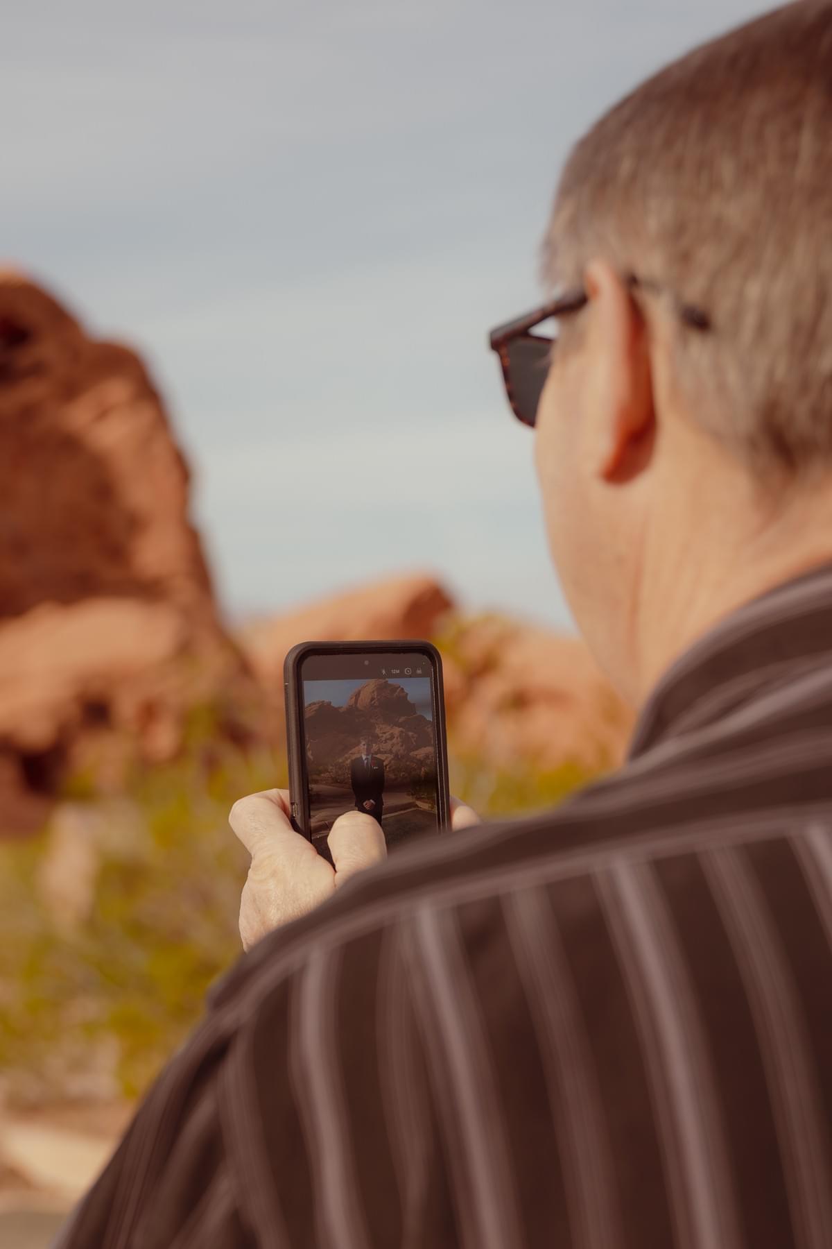 Multi-generational family lifestyle photography in Henderson, Nevada, featuring a grandfather capturing a photo of his grandson, by Falling Rocks Photography.
