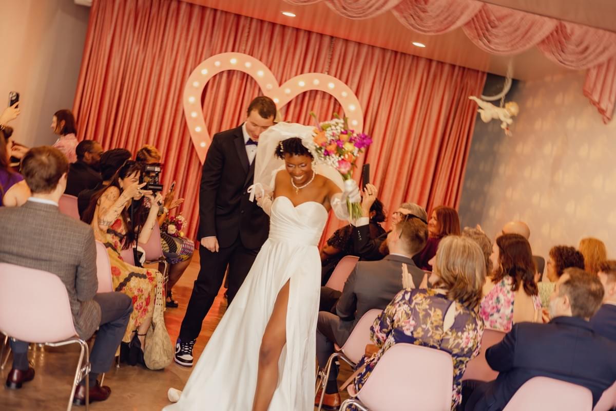 Couple walking down the aisle at Sure Thing Chapel in Las Vegas, surrounded by colorful decor and a lively wedding atmosphere.