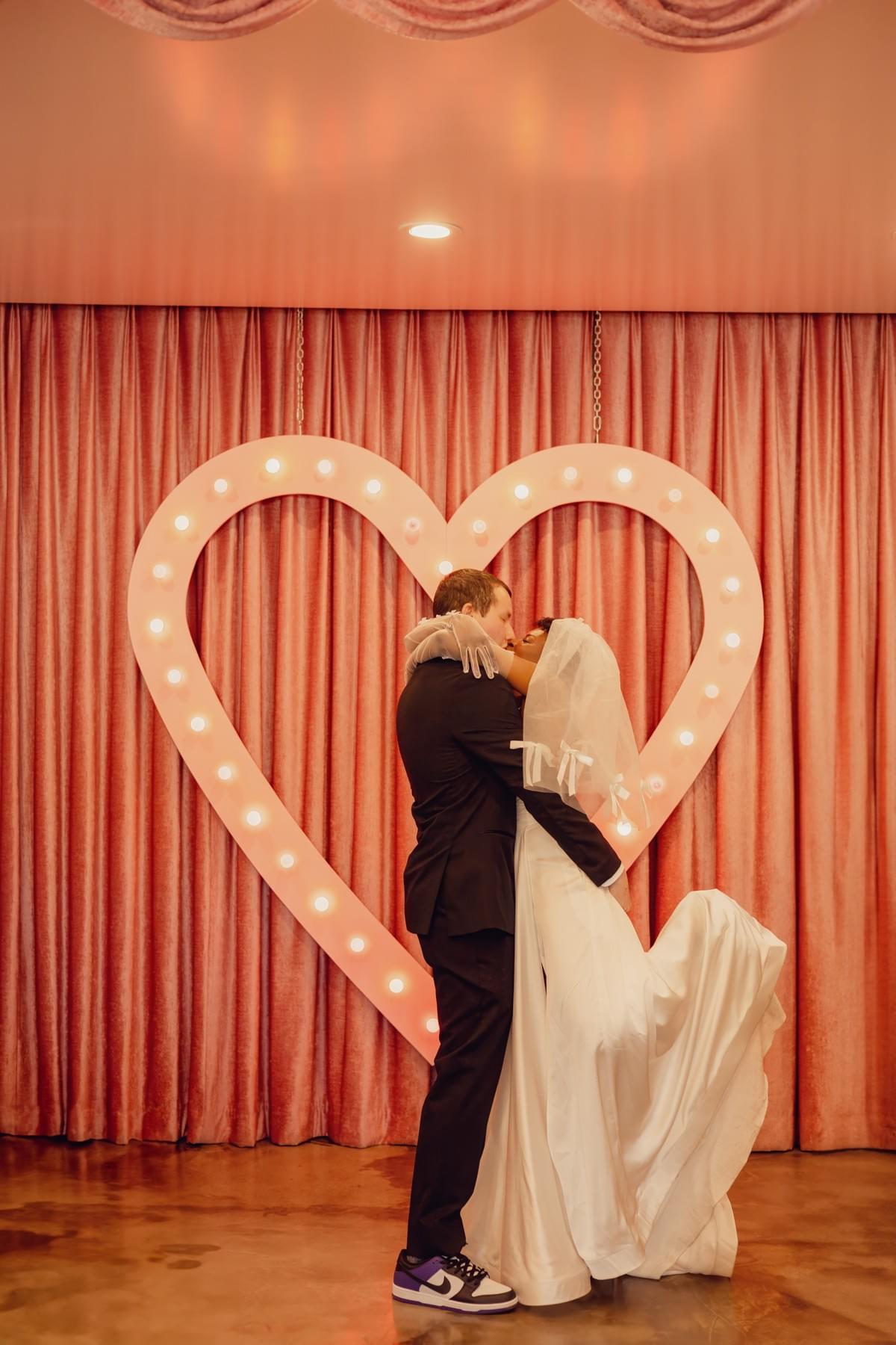 Couple sharing a romantic kiss at Sure Thing Chapel in Las Vegas during their Wedding and a Show ceremony, with vibrant lighting and Vegas energy.