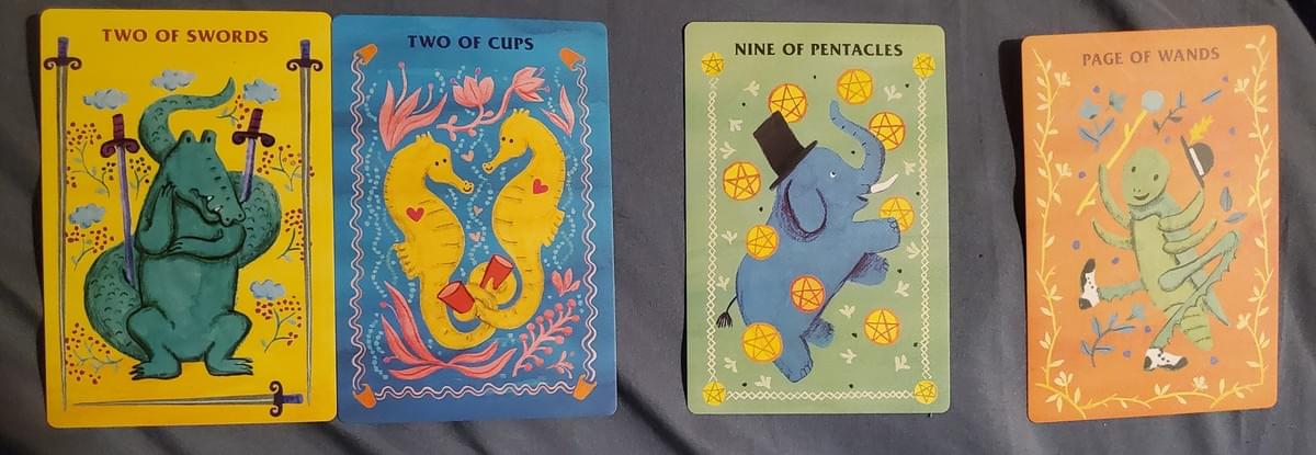 Picture Descriptions: 4 cards. 1 & 2.  Two of Swords:  An alligator has its tail wrapped around two swords and is deep in thought.  Two of Cups:  Two yellow seahorses are holding cups in their tails and have visible hearts, and are surrounded by pink, flowery kelp.  3.  Nine of Pentacles:  An elephant wearing a top hat is standing on its hind legs playing with all the shiny gold pentacles.  4.  A cricket with a bowler hat and black and white dress shoes does a little dance while holding a wand.