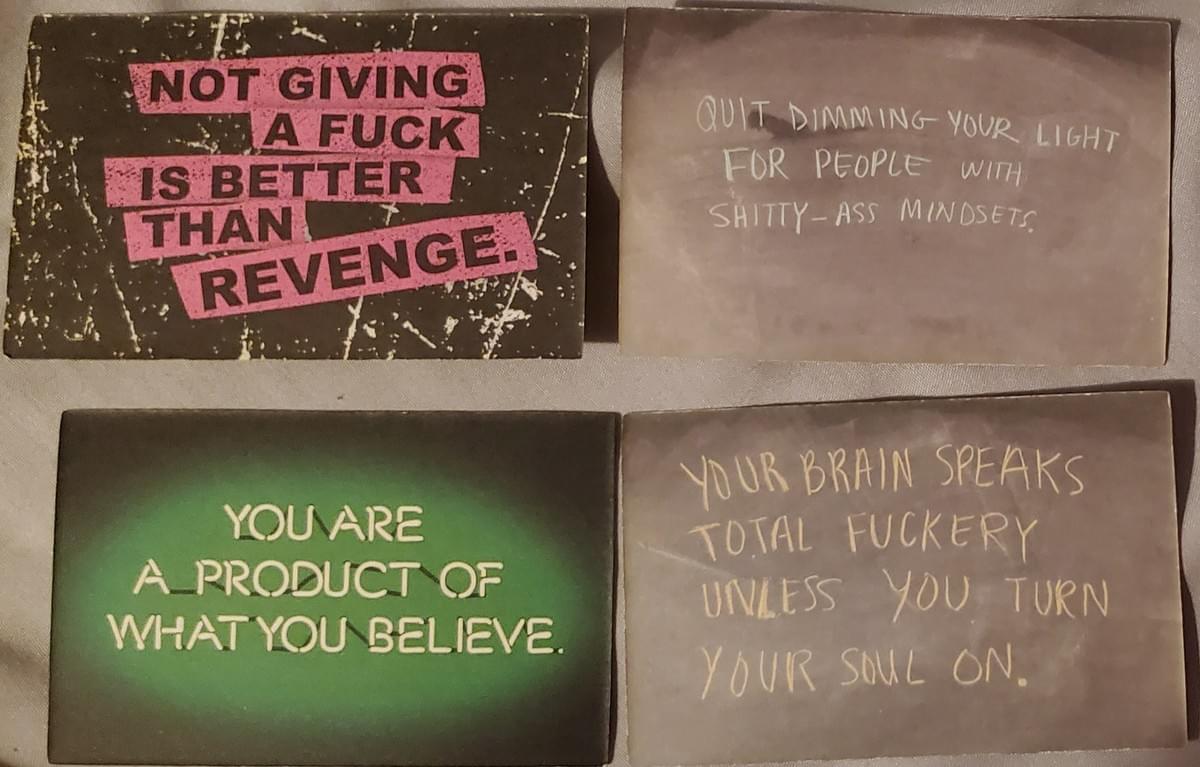 4 Cards.  1.  A card with a grainy black background and text on a pink background with black capital letters: “NOT GIVING A FUCK IS BETTER THAN REVENGE.”  2.  A greyish sepia card with white font – “QUIT DIMMING YOUR LIGHT FOR PEOPLE WITH SHITTY-ASS MINDSETS.”  3.  A green gradient circle with dark green edges and white text that looks like neon light that says “YOU ARE A PRODUCT OF WHAT YOU BELIEVE.”  4.  A grey card with white text that says “YOUR BRAIN SPEAKS TOTAL FUCKERY UNLESS YOU TURN YOUR SOUL ON.”