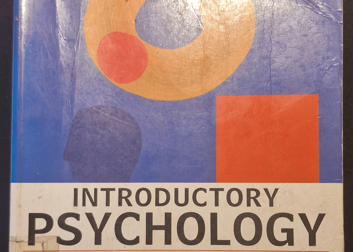 Cover of the book “Introductory Psychology” by Tony Malim and Ann Birch, featuring abstract geometric artwork with an orange ring, red circle, blue shape, and white cloud‑like form on a blue background; worn paperback textbook. Cover of the book “Introductory Psychology” by Tony Malim and Ann Birch, featuring abstract geometric artwork with an orange ring, red circle, blue shape, and white cloud‑like form on a blue background; worn paperback textbook.