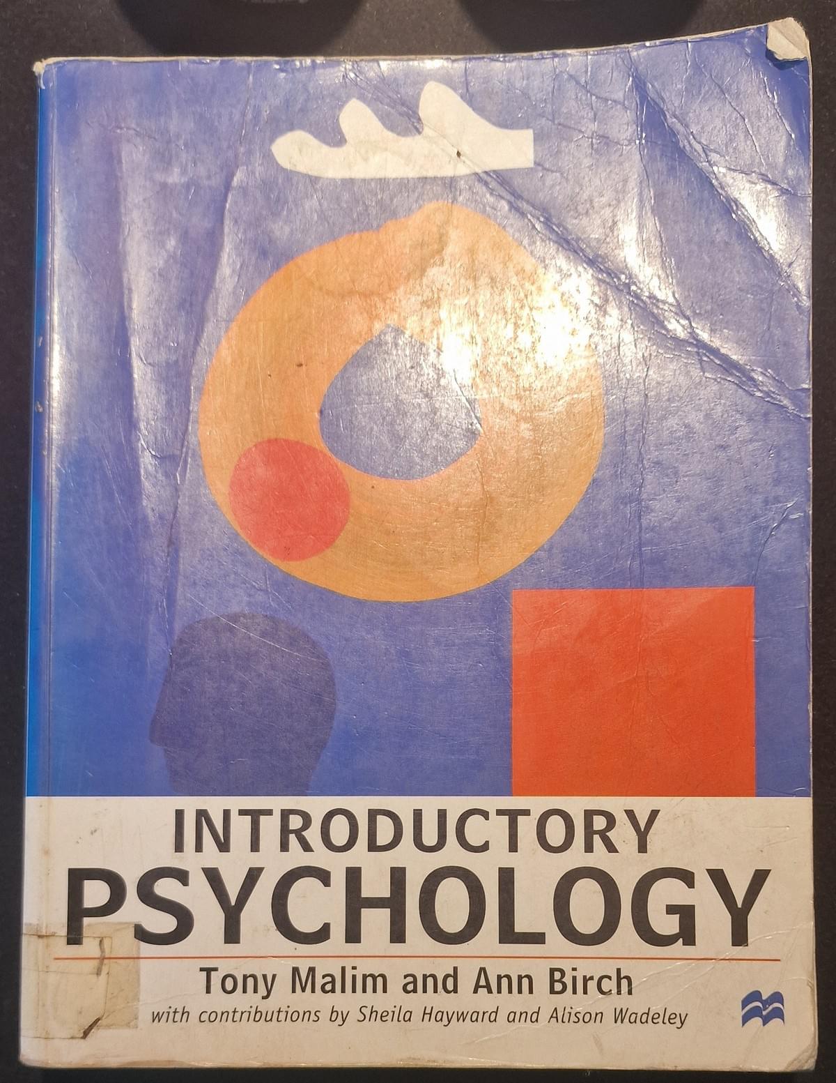 Cover of the book “Introductory Psychology” by Tony Malim and Ann Birch, featuring abstract geometric artwork with an orange ring, red circle, blue shape, and white cloud‑like form on a blue background; worn paperback textbook. Cover of the book “Introductory Psychology” by Tony Malim and Ann Birch, featuring abstract geometric artwork with an orange ring, red circle, blue shape, and white cloud‑like form on a blue background; worn paperback textbook.