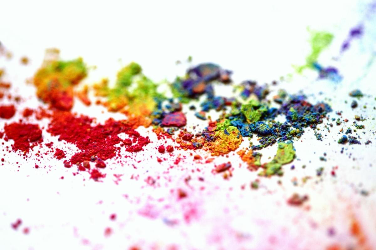 A vibrant cascade of glossy paint drips flows down a white surface, arranged in a smooth, continuous spectrum. The colors transition fluidly from red, orange, yellow, green, cyan, blue, purple, pink, and loop back to yellow and green, creating a dynamic and visually striking composition. Each drip is thick and lustrous, forming organic, elongated shapes that evoke movement and spontaneity. The white background enhances the intensity of the hues, while the overall layout suggests creativity, emotional expression, and artistic freedom. The image captures the tactile beauty of paint in motion, celebrating color theory and the sensory appeal of visual art