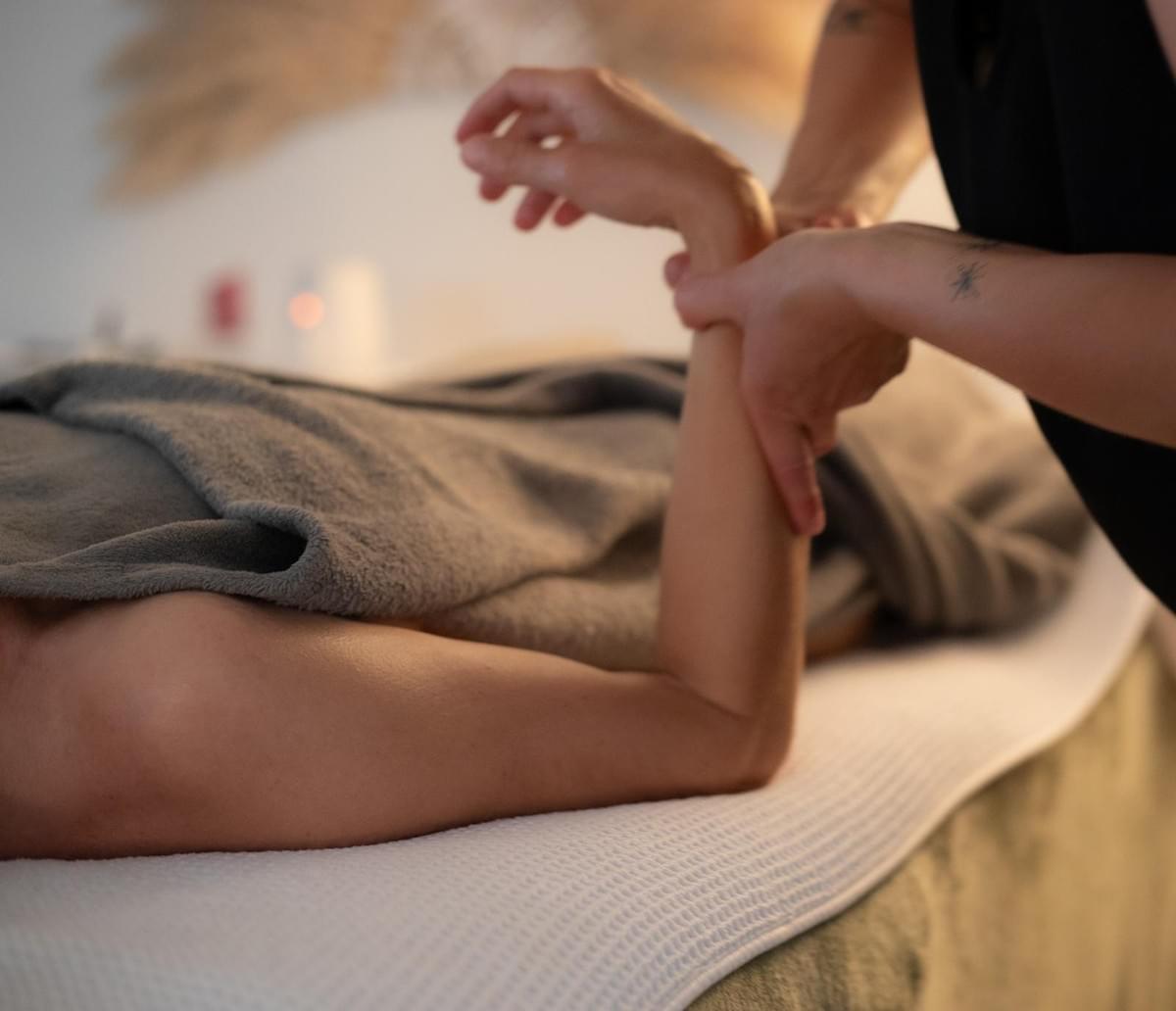 Masaje relajante del brazo en un ambiente suave y cálido, en el estudio Les Alchimistes en Labenne
