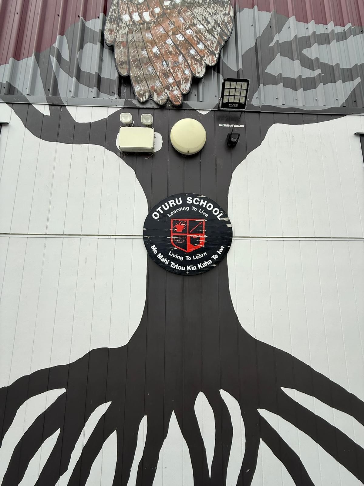 A Tree painted on tne sidfe of a school in Aotearoa featuring the shield for Oturo school