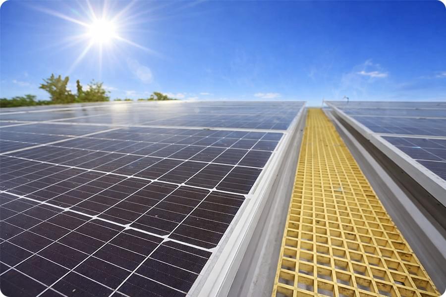 Vue rapprochée de panneaux photovoltaïques par temps chaud et ensoleillé, montrant les reflets intenses à la surface des modules et les détails de l’installation