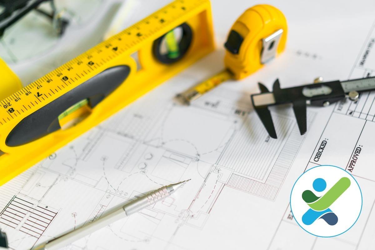 A tape measure, pencil, level and vernie calipers are placed on top of an architectural drawing