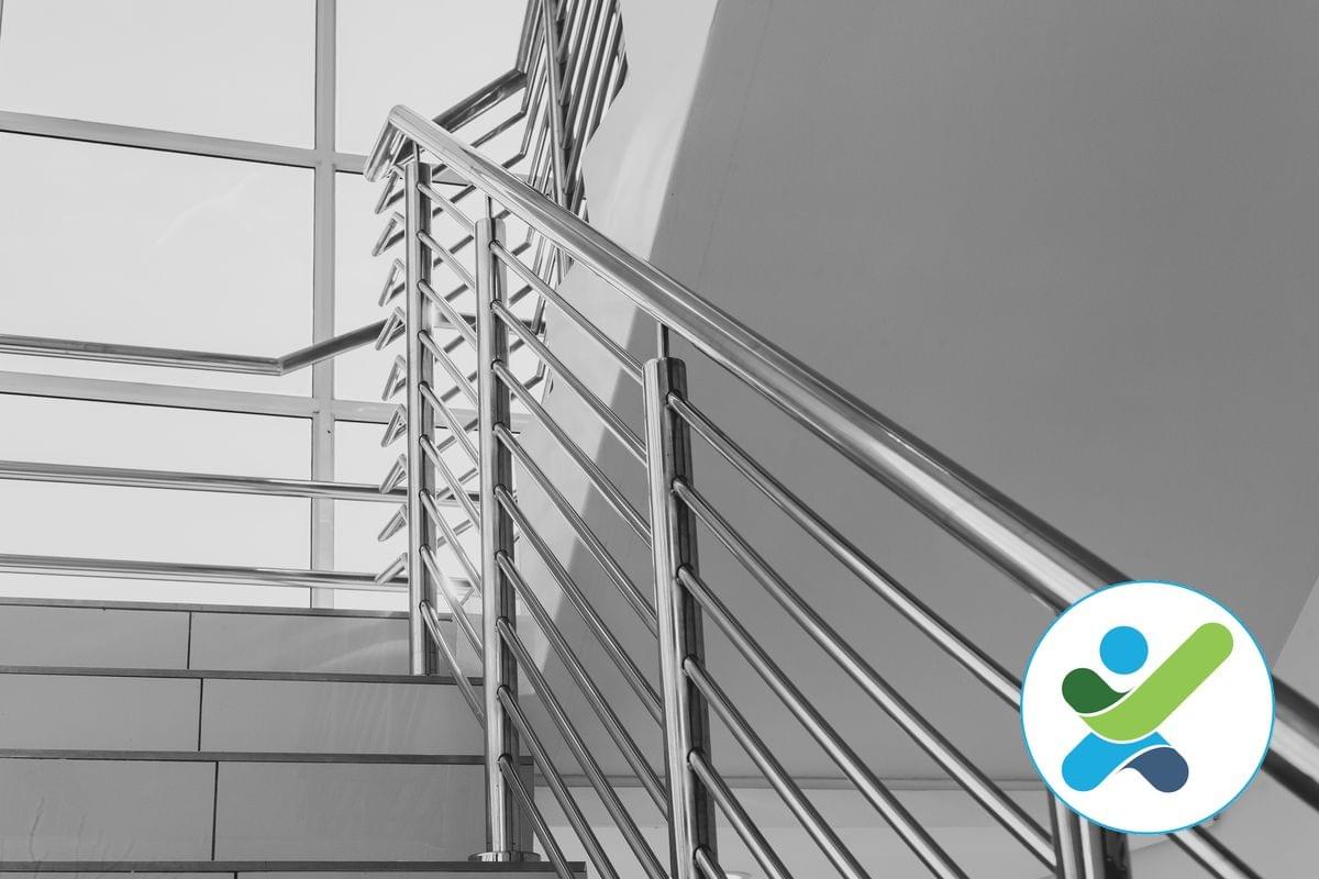 A view looking up a modern stairway with a single stainless steel handrail