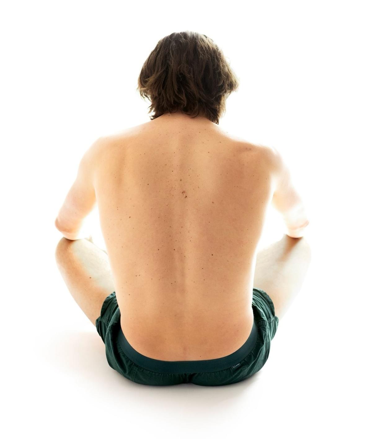 Back view of a man’s body, shoulders slightly hunched — representing how stress lives in the body.