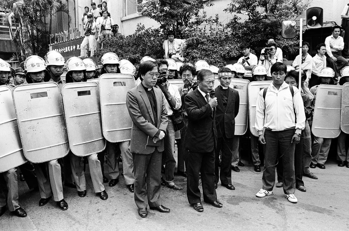 在鎮暴警察圍視下，手持麥克風帶領大家一同祈禱。（邱萬興／攝）