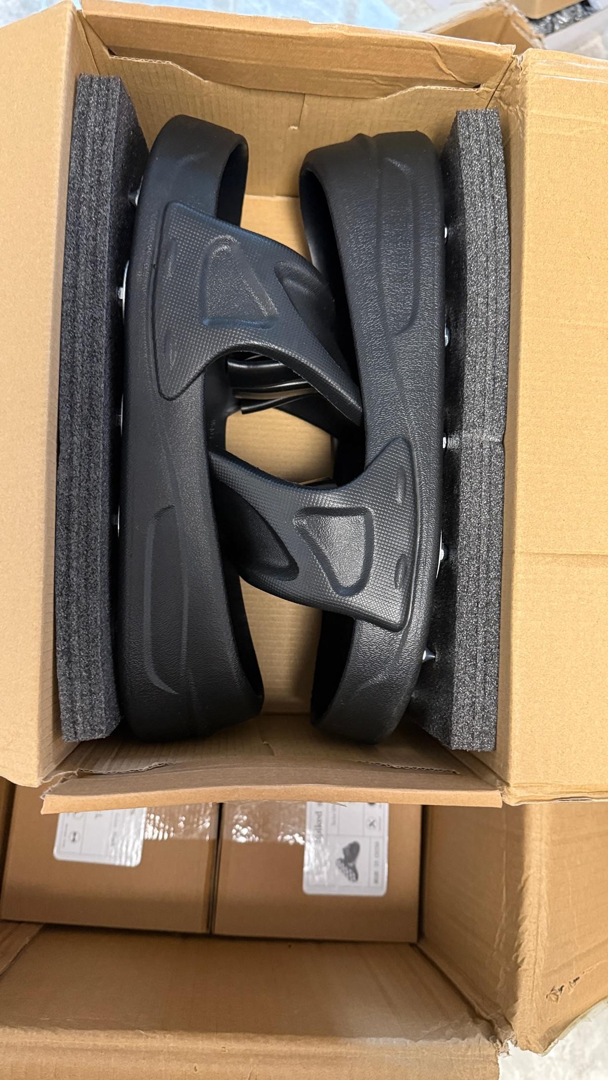 Boxed black spike shoes for floor coating work, showing size L packaging and protective foam before shipment.