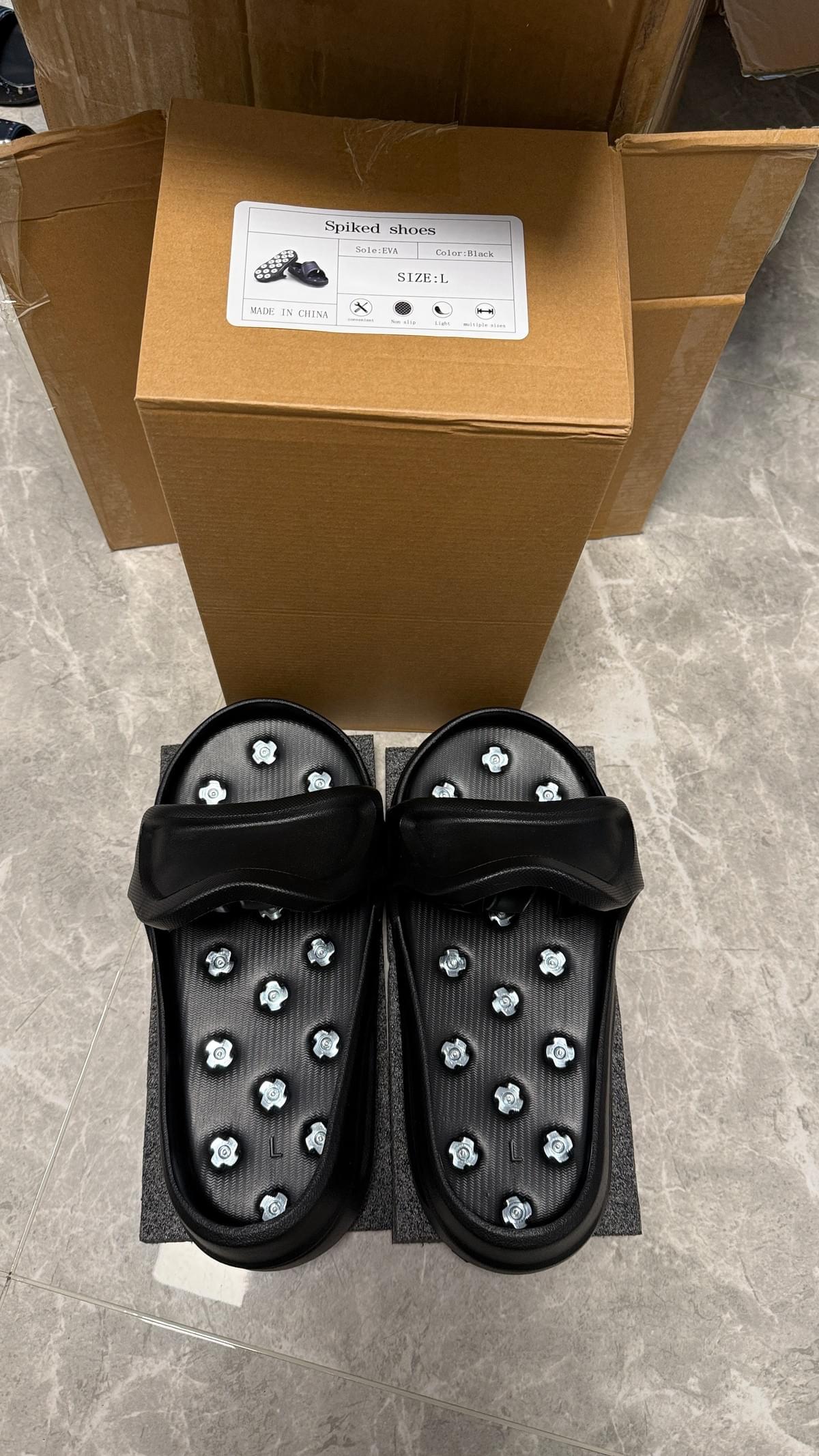 Black size L spike shoes for epoxy floor coating and self-leveling work, shown with box packaging before shipment.