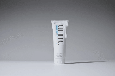 Unite 7Seconds BlowOut Crème tube standing on a neutral surface with product cream draped over the cap. Unite 7Seconds BlowOut Crème tube standing on a neutral surface with product cream draped over the cap.