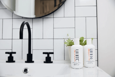 UNITE BOING Defining Curl Cream and Moisture Curl Cream displayed beside a bathroom sink, highlighting curl care products. UNITE BOING Defining Curl Cream and Moisture Curl Cream displayed beside a bathroom sink, highlighting curl care products.