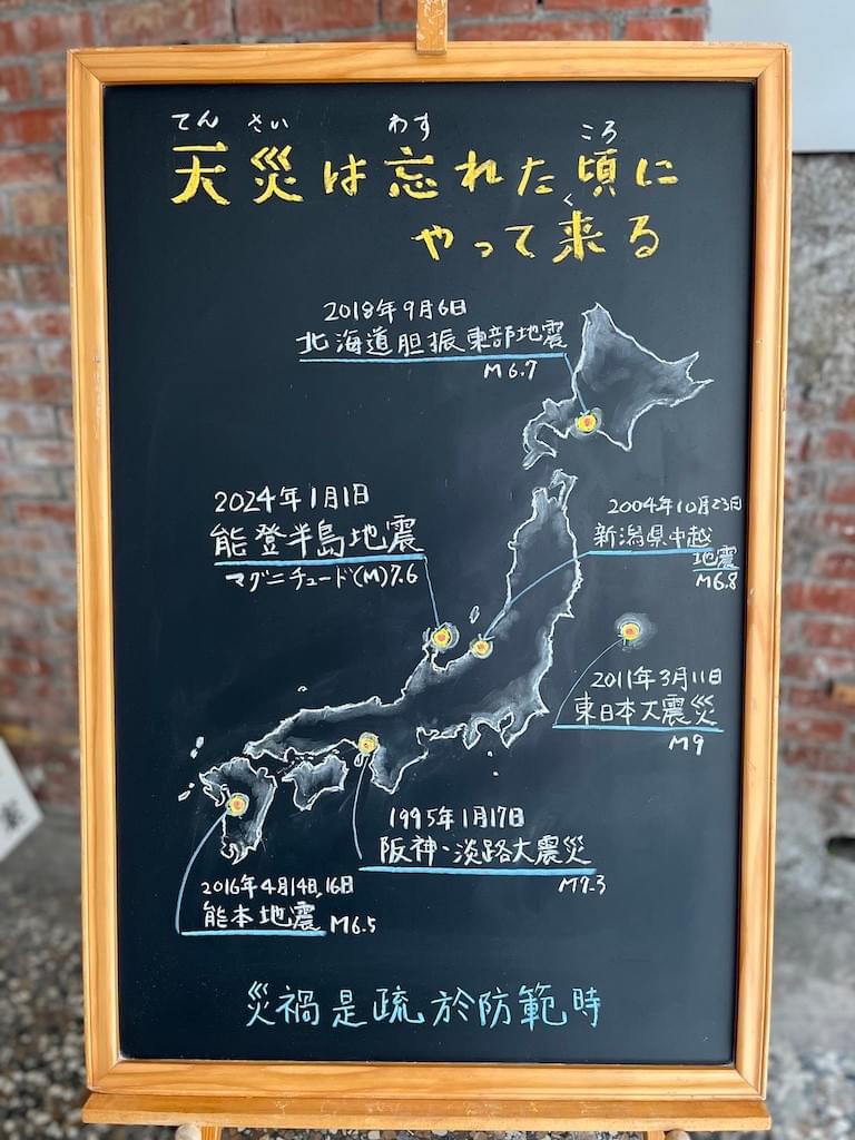 小さい黒板にチョークで絵が描いてあります。日本語のことわざ・慣用表現を紹介するための絵です。上部に横書きで「天災は忘れた頃にやって来る」と書いてあり、下部に日本地図のイラストが書いてあります。そして、過去の大地震の震源地が記してあります。 上から 2018年9月6日北海道胆振東部地震 2024年1月1日能登半島地震 2004年10月23日新潟中越地震 2011年3月11日東日本大震災 1995年1月17日阪神・淡路大震災 2016年4月14日、16日熊本地震