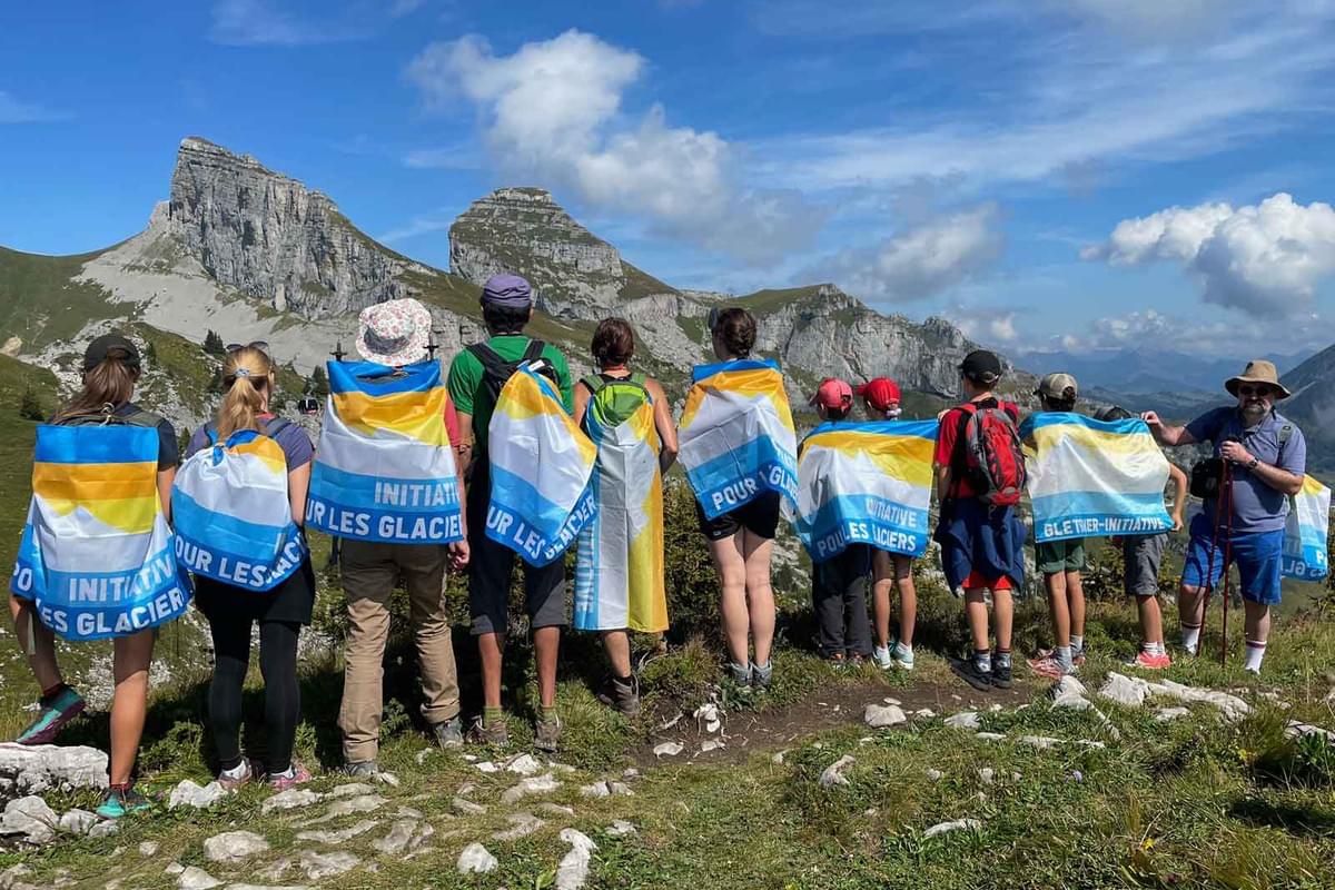 Des personnes engagées se promènent avec le drapeau de l'Initiative pour les glaciers.