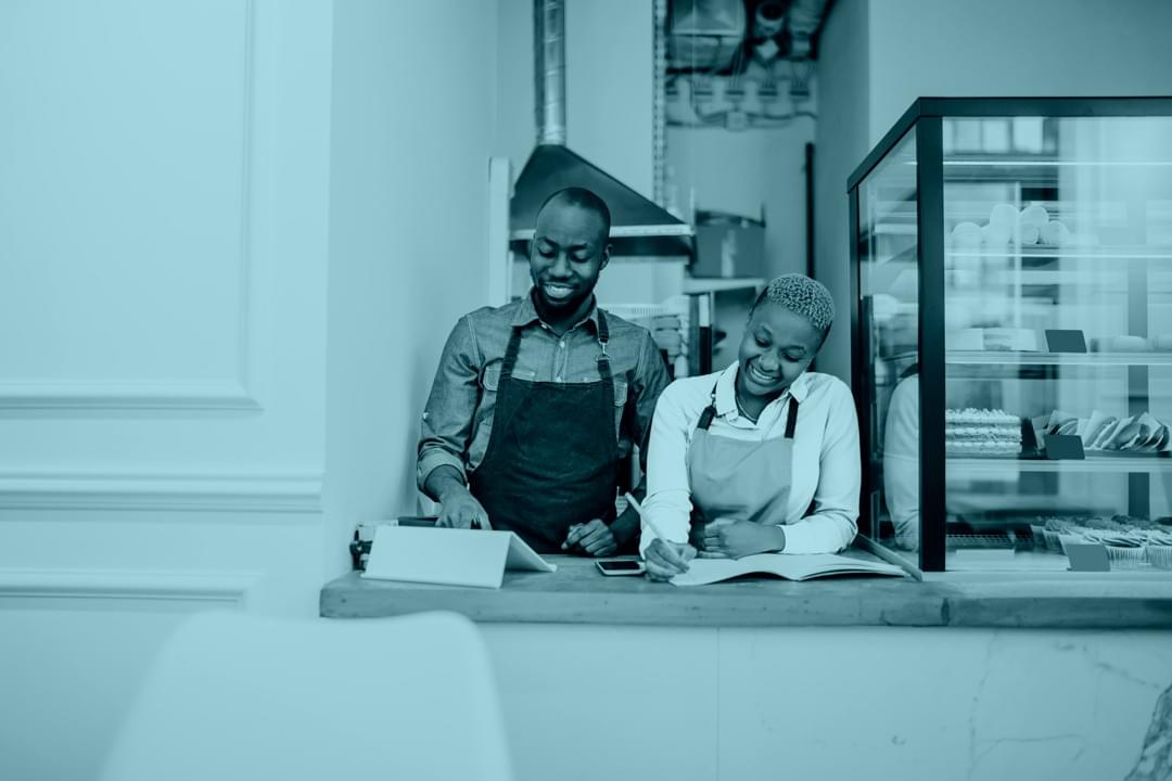 wo small business owners reviewing orders and smiling behind a bakery counter, representing successful startup branding and digital growth