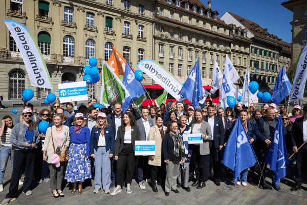 Gruppenbild mit vielen Personen, Fahnen von Organisationen und blauen Familienzeit-Ballonen beim Start der Unterschriftensammlung auf dem Bundesplatz.