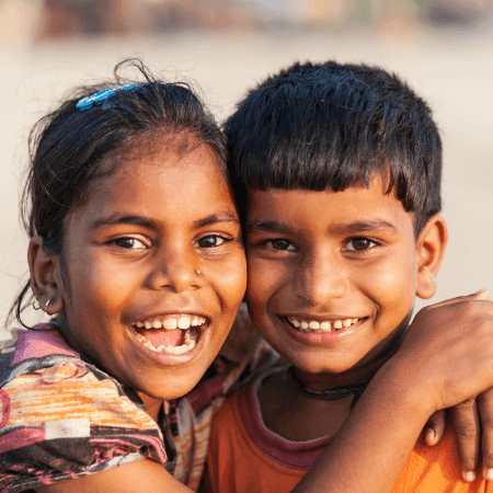 Young girl smiling while embracing a younger boy, showcasing sibling affection