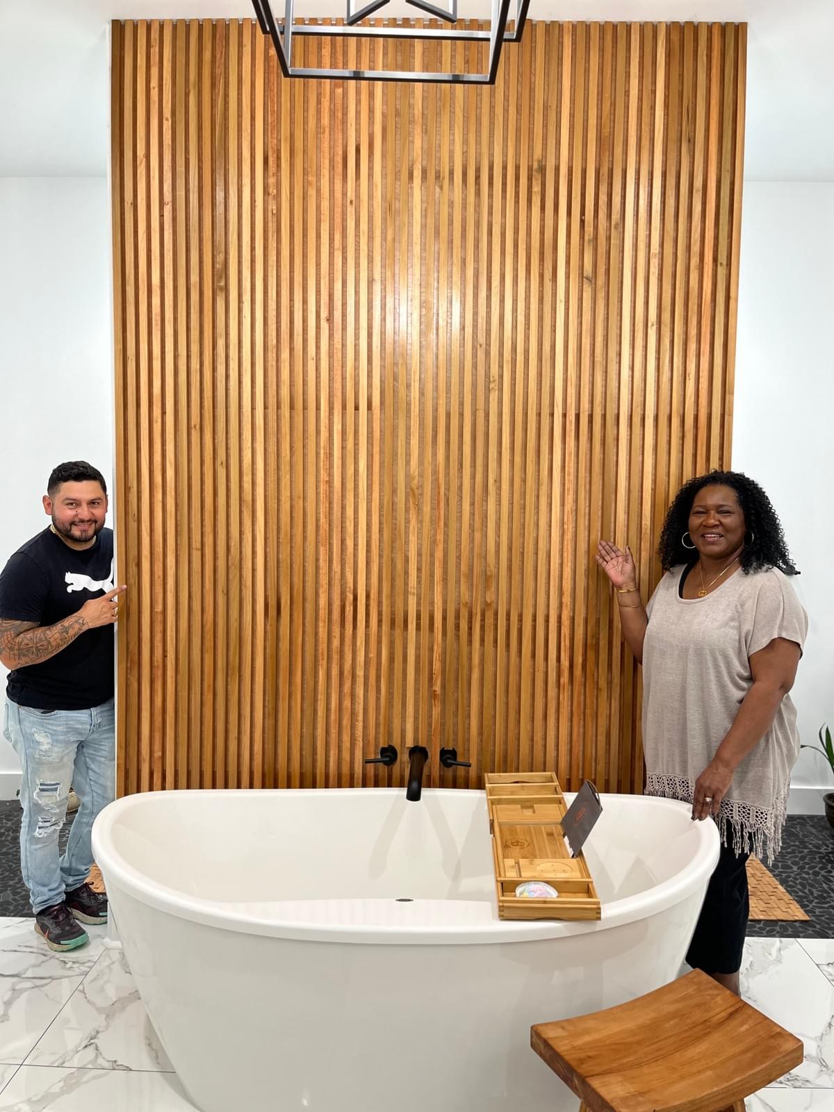 Team member creating a focal point in bath design with warm wood tones and a neutral color palette and cozy furnishings.