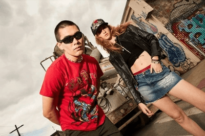 Two people wearing graphic streetwear outfits, including a red dragon-print tee, denim skirt, and leather jacket.