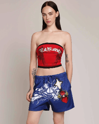 Woman modeling a red Ed Hardy tiger graphic tube top with lace trim and blue printed mesh shorts.