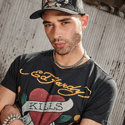 Man in a black cap and Ed Hardy T-shirt with a rhinestone heart graphic reading "Love Kills." Man in a black cap and Ed Hardy T-shirt with a rhinestone heart graphic reading "Love Kills."