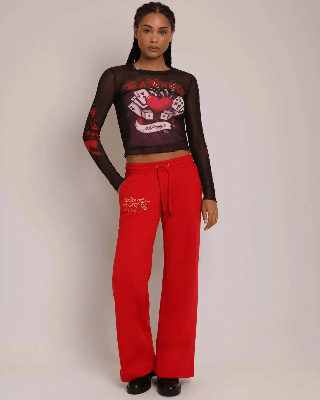 Woman in a sheer black Ed Hardy playing-card graphic top and red wide-leg sweatpants.