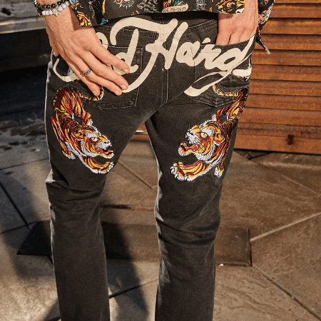Back view of Ed Hardy black denim jeans featuring embroidered tiger designs and signature logo across the waistband.