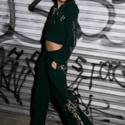 Woman in a dark green Ed Hardy fleece set with gold rose graphics, posing by a graffiti-covered shutter.