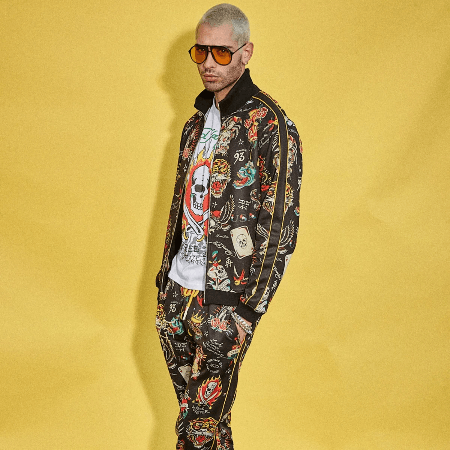 Ed Hardy men's all-over tattoo print track jacket and pants set with graphic tee on yellow background.