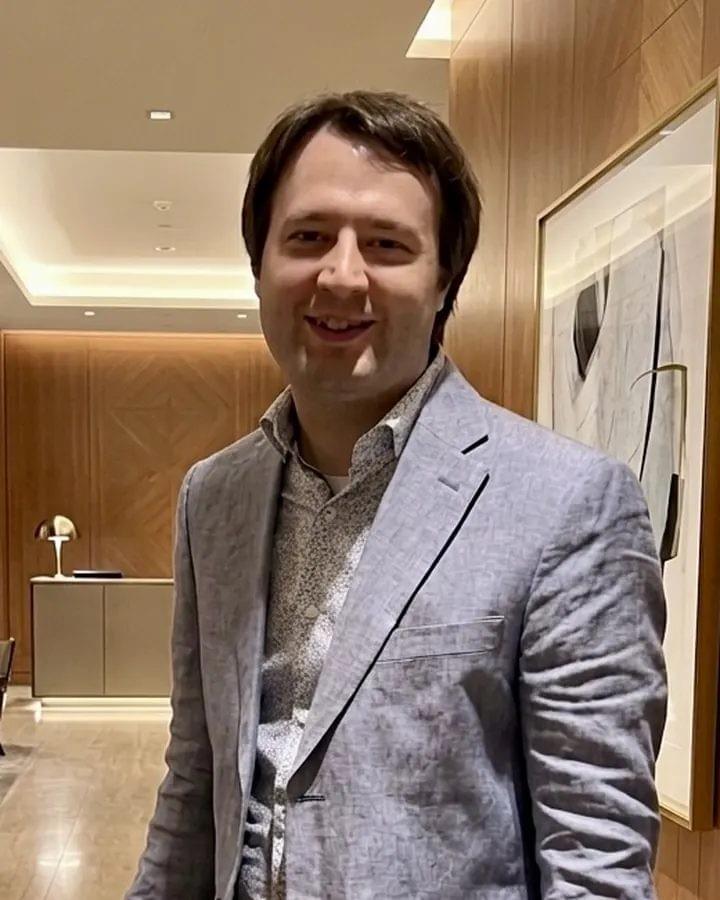 Dustin Craig, smiling, in a light grey jacket.