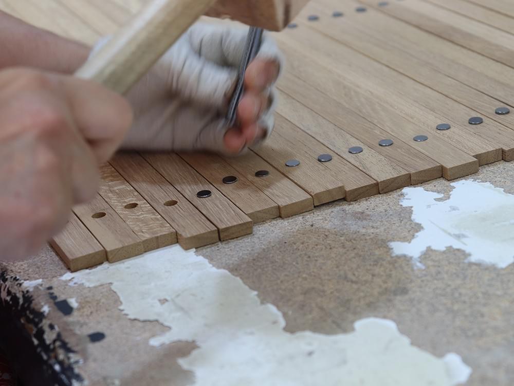 Worker installing magnets in wooden poster hanger strips during production