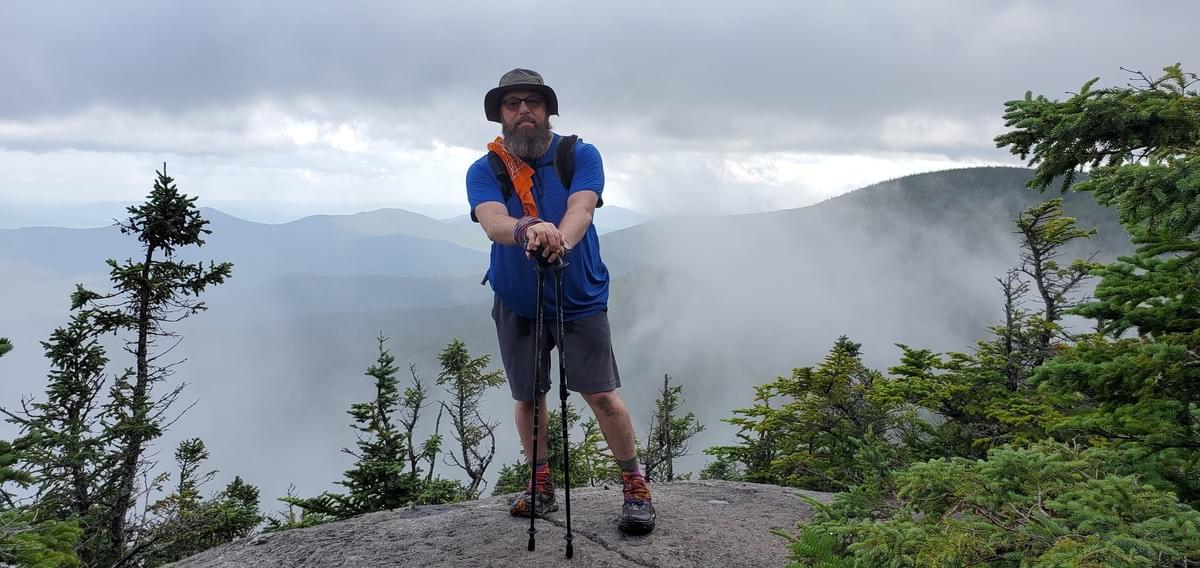John Ironheart Kolker on a ridge in the clouds with trekking poles on the Appalachian Trail