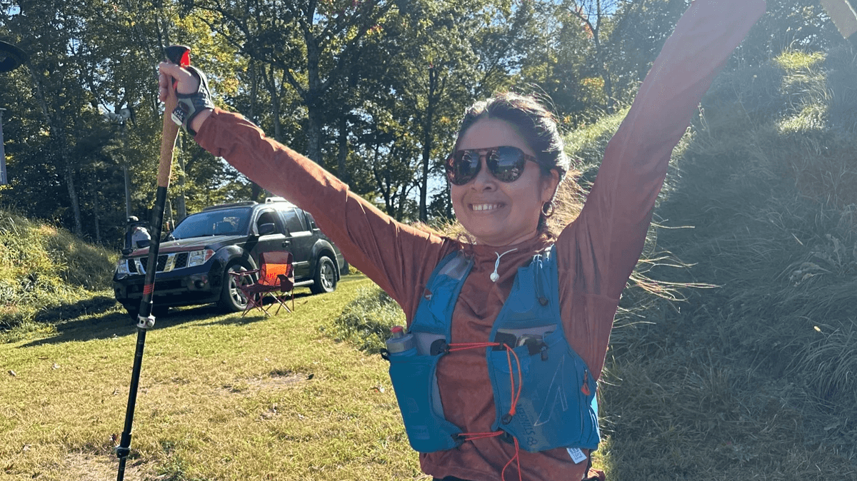 Michelle Perone with arms raised and trekking poles at IronHike